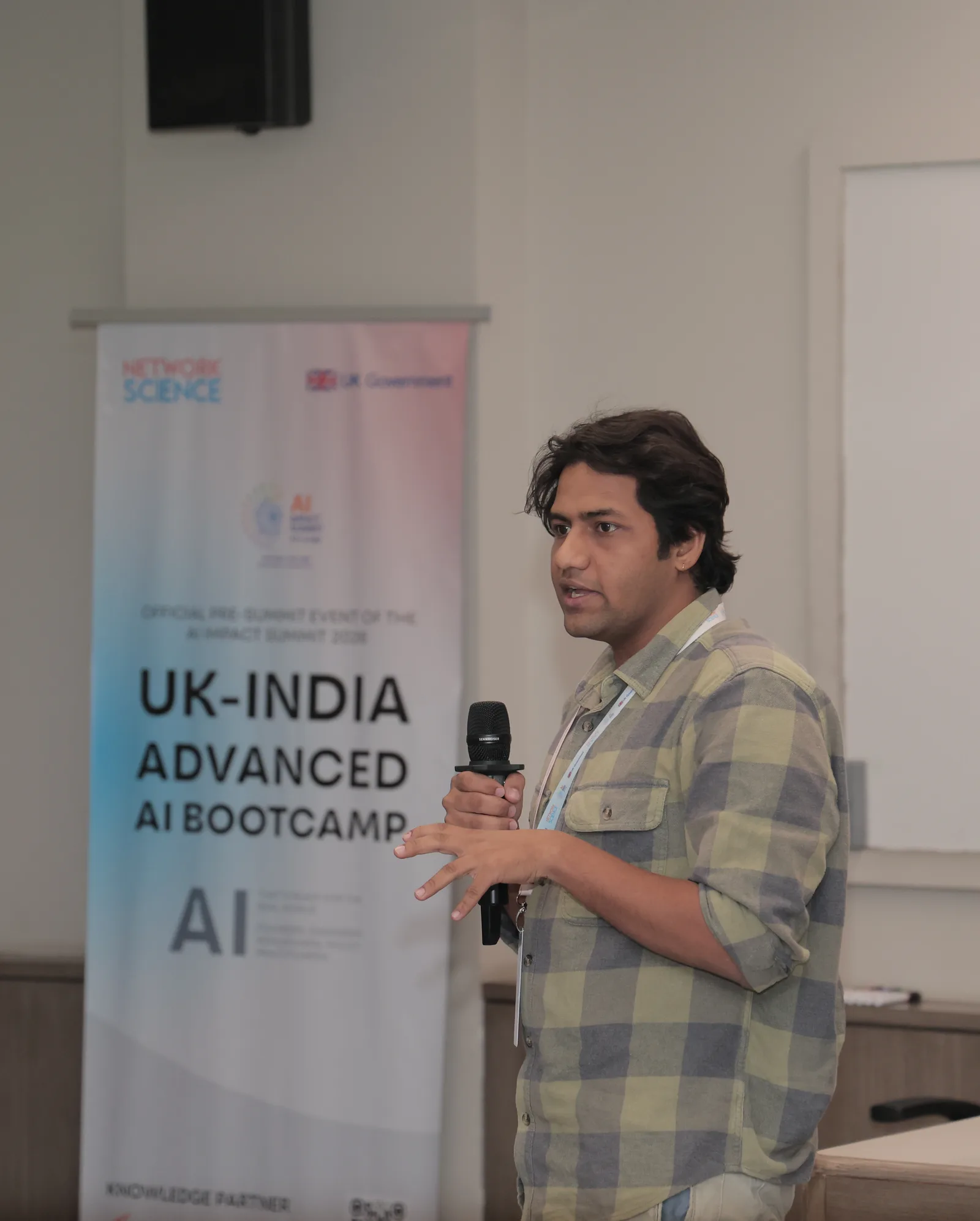 Vrushabh Jain presenting with a microphone at the UK-India Advanced AI Bootcamp